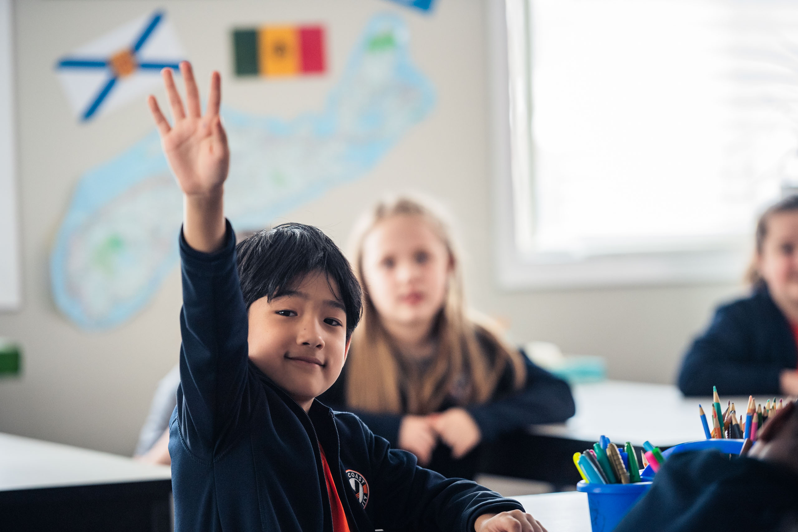 A young student raising their hand in class.